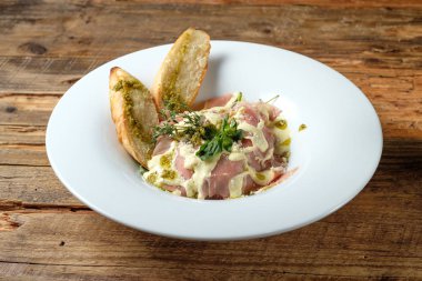 Jambon makarna ahşap masa üzerinde pesto sos ile