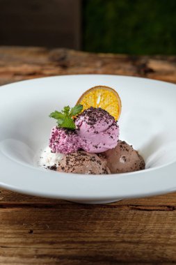 Dondurma topları nane ile üç tür ve ahşap arka plan üzerinde turuncu bir dilim