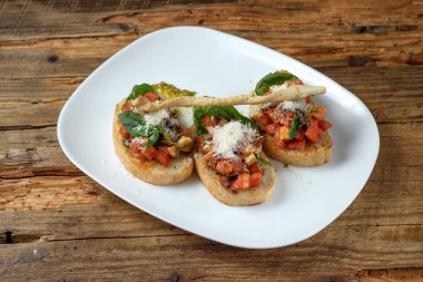 Bruschetta taze domates, parmesan ve fesleğen ahşap arka plan üzerinde