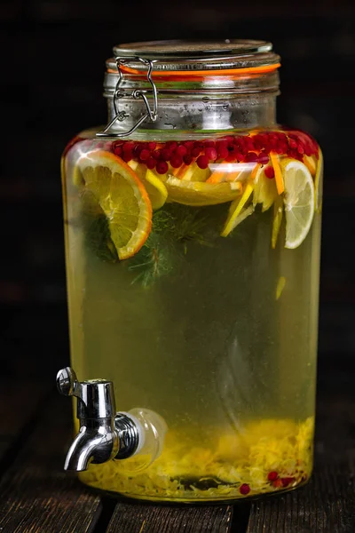 Homemade lemonade in beverage dispenser with fresh fruits on woo