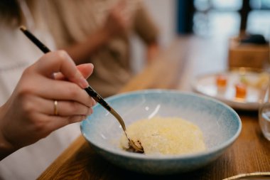 Ton balıklı tartar tadında bir kadın eli. Masada krema var. Yakın görüş.