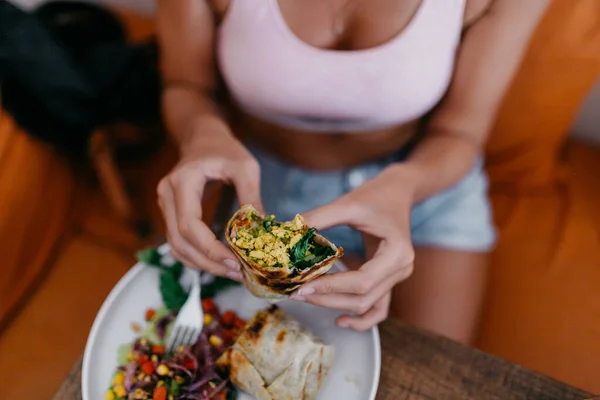 Kvinna Äter Wrap Smörgås Med Grönsaker När Sitter Vid Bordet — Stockfoto
