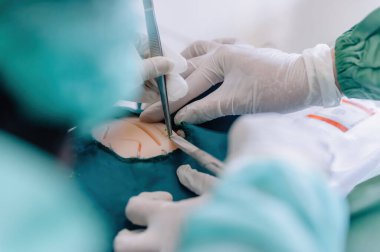 Tıp öğrencileri bebek mankeni üzerinde dikiş pratiği yapıyor. Cerrahi eldivenli bir ekip çok önemli bir beceri öğreniyor.