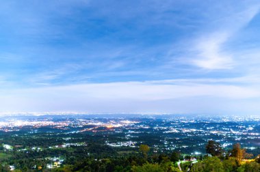 Şehir ışıklarının yamaçtaki ormandan çarpıcı gece manzarası, kentsel ışıltıyı yıldızlı gökyüzünün altında sakin doğal manzarayla harmanlıyor..