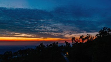 Şehir ışıkları ve orman tepeleri üzerinde sersemletici bir gün doğumu, sıcak gökyüzü renkleriyle Highland 'ın ışıldayan şehir manzarasını harmanlıyor.