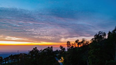 Şehir ışıkları ve orman tepeleri üzerinde sersemletici bir gün doğumu, sıcak gökyüzü renkleriyle Highland 'ın ışıldayan şehir manzarasını harmanlıyor.