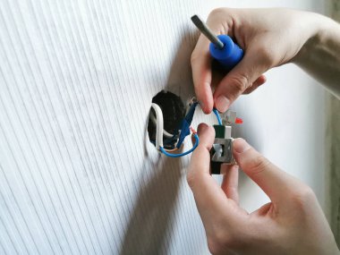 Elektrikçiler tamir eder. Duvar kâğıdı yaptıktan sonra tornavidayla prizi yerleştirmek.