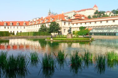 Wallenstein Garden 'daki bir göldeki yansıma, heykelleri ve çeşmesi, kırmızı kiremitli çatısı, canlı mavi gökyüzüne ve beyaz bulutlara karşı gündüz vakti. Prag, Çita Cumhuriyeti.