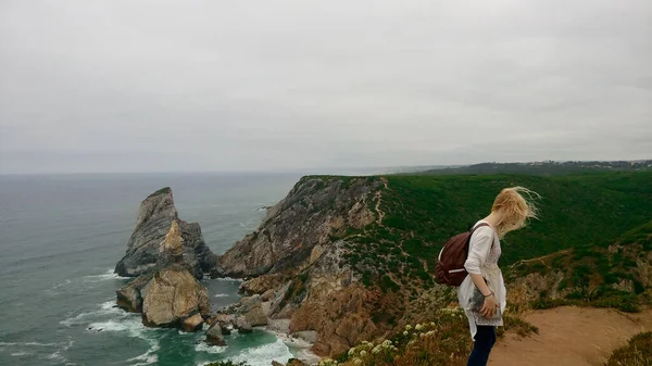 在岩石和海洋背景上的金发女孩 悬崖边的女游客正在看大西洋 葡萄牙 — 图库照片#