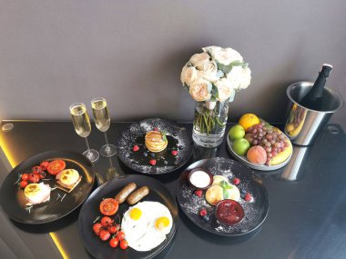Şampanya, yumurta, krep, cheesecake ve yeni evliler için şampanya ile şenlikli bir kahvaltı. Güllü ve yiyecekli şenlik masası..