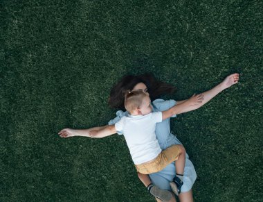 Anne ve oğlu yazın parkta gezinirken yeşil çimlerin üzerinde yatıyorlar. Çocuk ve anne kollarını çarmıha germiş bir şekilde uzanır, kuşlar gibi, birbirlerine sarılırlar. Üst Manzara. Metin için yer