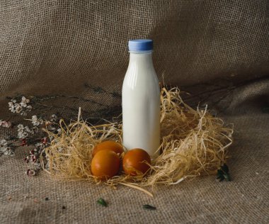Bir şişe süt ve yumurta. Çuval bezi arkaplanındaki rustik biçim