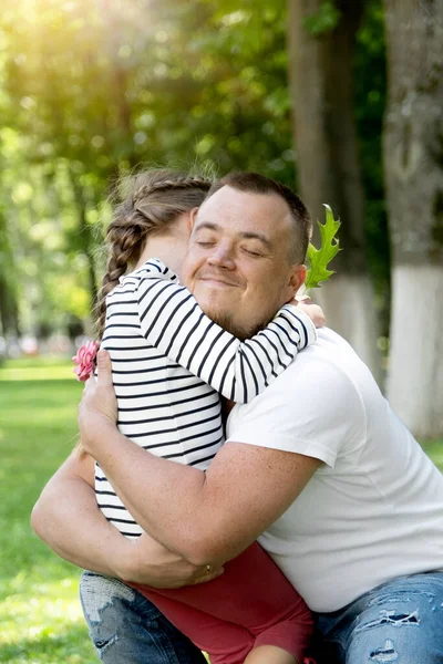 Portrait of a happy caucasian dad hugging his daughter. The family spends the weekend in the park on a sunny summer day. Father\'s day.