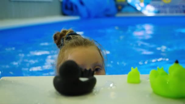 Menina na piscina esportiva brinca com brinquedos de borracha — Vídeo de Stock