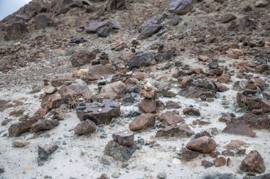 Hindistan 'ın uzak Himalaya çöllerinde düzgünce istiflenmiş taş cairns. Geleneksel kabileler, engebeli dağ manzaralarına karşı oluşturulan rehberliği, meditasyonu ve maneviyatı sembolize eder. Seyahat, kültür, doğa ve farkındalık temaları için mükemmel..