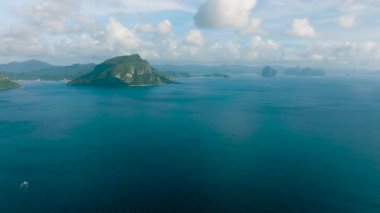 Açık mavi gökyüzü ve bulutların altında mavi denizle çevrili tropikal adalar. El Nido, Palawan. Filipinler.