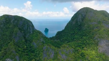 Kireçtaşı kayaları canlı yeşil bitkilerle çevrili, barışçıl bir manzara yaratıyor. El Nido. Palawan, Filipinler.