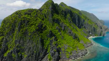 Tapiutan Adası 'ndaki Rocky sahilleri ve yüksek tepeler. Şeffaf turkuaz su ve mavi deniz. El Nido, Palawan. Filipinler.