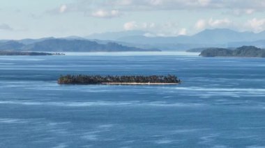Tropikal adada palmiye ağaçları olan beyaz kumlu bir sahil. Mavi deniz, mavi gökyüzü ve bulutlar. Mindanao, Filipinler. Büyüt.