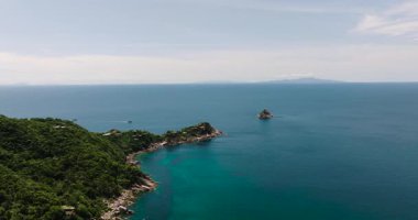 Palmiye ağaçları ve tropikal yapraklar kıyıya yakın teknelerle turkuaz bir denizi sınırlandırır. Koh Tao, Tayland.