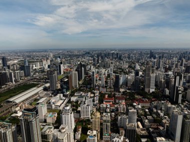 Modern binaların ve konut kulelerinin yer aldığı şehir silueti, arka planda açık gökyüzü. Bangkok, Tayland.
