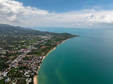 Kumlu plajları ve bulutlu bir gökyüzünün altında ufka uzanan sakin turkuaz suları olan bereketli tropikal sahil şeridi. Tayland, Koh Samui.