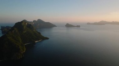Gün batımı gölgeli adaların manzarası. El Nido, Palawan, Filipinler 'deki adalar üzerinde yemyeşil tepeler ve kireçtaşı kaya oluşumları.
