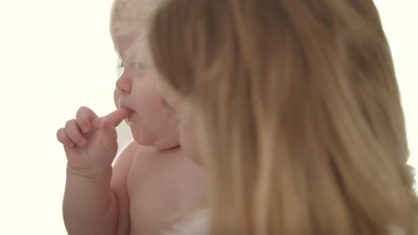 Adorable bebé comiendo dedo. Niño desnudo con el dedo en la boca en las manos madre — Vídeo de stock