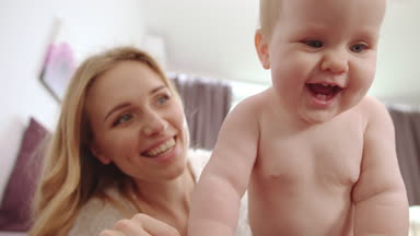 Beş dişli gülümseyen çıplak bir bebek. Mutlu bebek, anne gülümsüyor ve eğleniyor.