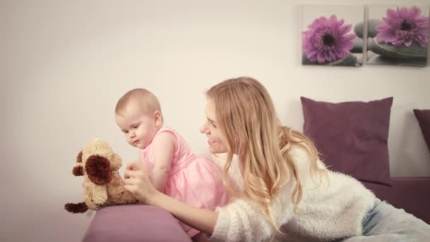 Moeder die met de baby speelt. Mooie baby spelen met speelgoed op bed — Stockvideo