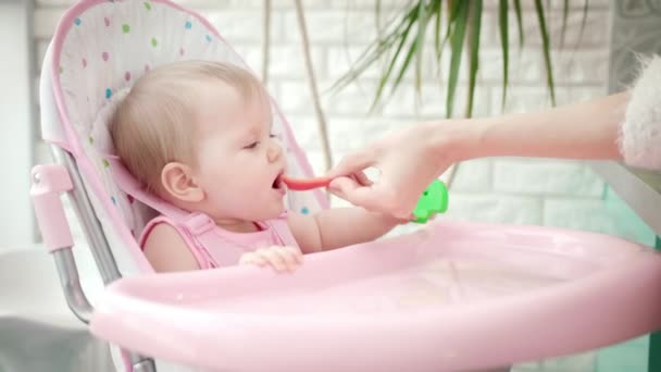 Sweet baby girl eating vegatable. Mother hand feeding child with red pepper — Stock Video