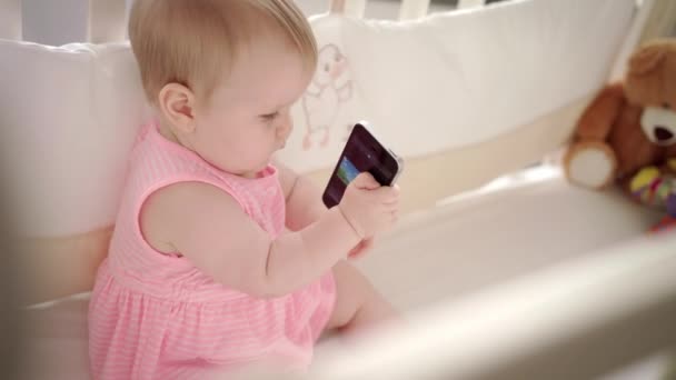 Concepto de entretenimiento infantil. Lindo bebé con móvil viendo animación en la cama — Vídeos de Stock