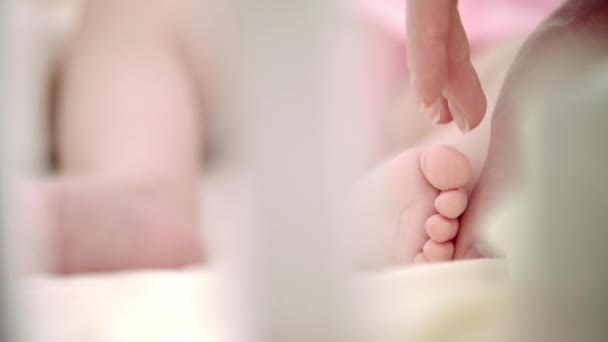 Руки матери гладят детские ноги. Мать защищает ребенка. Новая жизнь — стоковое видео