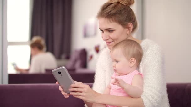 Selfie anne ve kızı evde. Çocuklu güzel bir kadın telefonuyla fotoğraf çekiyor. — Stok video