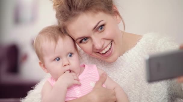 Mãe sorridente fazendo foto selfie com bebê menina. Mulher com criança foto móvel — Vídeo de Stock