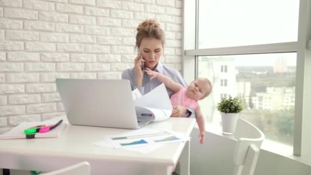 Деловая мать с ребенком разговаривает по мобильному телефону. Женщина работает с ребенком — стоковое видео