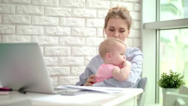 Business woman embracing girl in home office. Tired baby in mother embrace — Stock Video