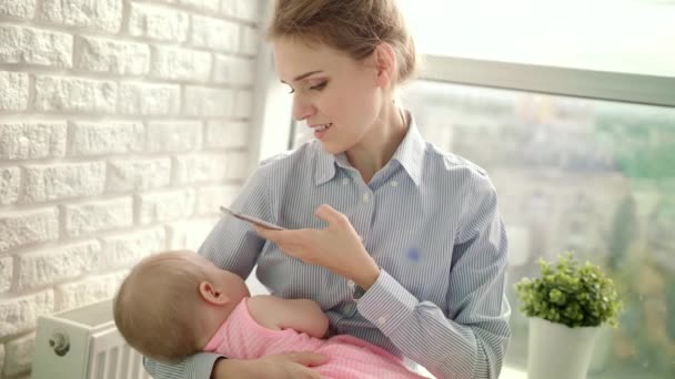 Gyönyörű nő ingben, aki mobilképet készít a lányról. Anya fotózza a babát. — Stock videók