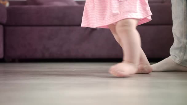 Petite fille faisant les premiers pas de sa vie. Marche d'apprentissage des nourrissons. Petit pas de pieds — Video