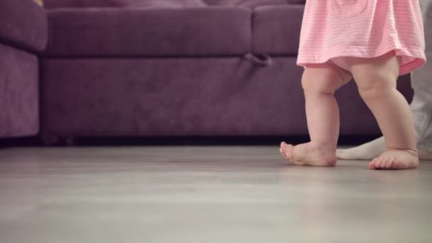 Gyerek láb sétál a földön. Babalábak bámulnak otthon. A gyermek első lépése — Stock videók