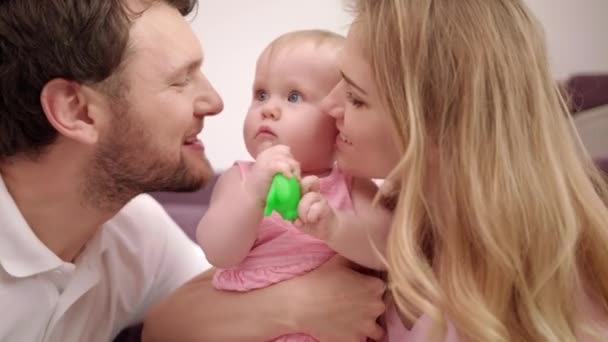 Madre feliz con padre sosteniendo al bebé en las manos. Mamá y papá beso dauther — Vídeo de stock