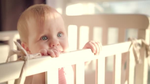 Bayi berdiri di tempat tidur di rumah. Potret bayi perempuan berdiri di tempat tidur. Mata bayi — Stok Video
