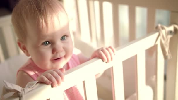 Liebenswertes Baby reicht Hand in Hand Kinderbett. Kleines Kind mit interessantem Gesicht — Stockvideo