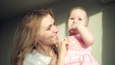 Mutlu anne kucağında bebeği tutuyor. Neşeli anne küçük kızı kucakla.