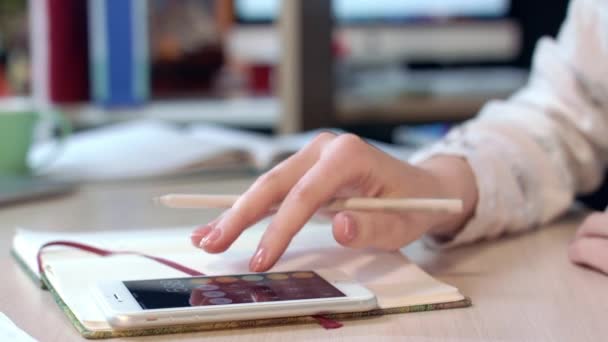 Mano femenina usando el teléfono móvil para calcular beneficios en el lugar de trabajo — Vídeos de Stock