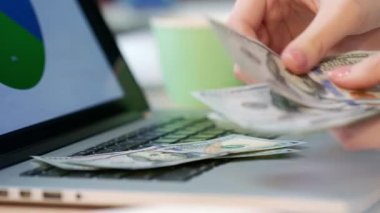 Kadın el para sayma ve dizüstü klavyede koymak. Çevrimiçi finansal işlemler. Erkek sayım para nakit eller. Online iş para kavramı