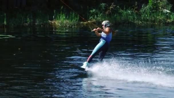 Mulher do esporte a bordo deslizando na água. Menina estudando wakeboarding no lago — Vídeo de Stock