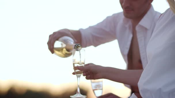 Schöner Mann, der Champagner in Weingläser gießt. Liebespaar entspannt im Freien — Stockvideo
