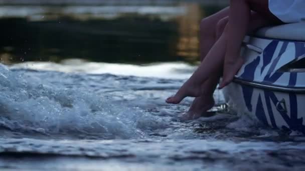 Piernas humanas en flujo de agua espumosa. Amor pareja paseos en barco en el río por la noche . — Vídeo de stock