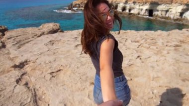 Güzel kadın gülümseyerek ve kayalık uçurum elini tutarak güneş gözlüğü